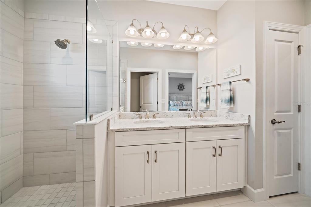 2516 Coral Court Indian Rocks Beach, FL 33785 - Photo 47 of 69 a bathroom with a granite countertop sink a large mirror and a shower
