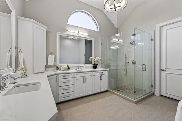 a spacious bathroom with a shower a sink and a mirror