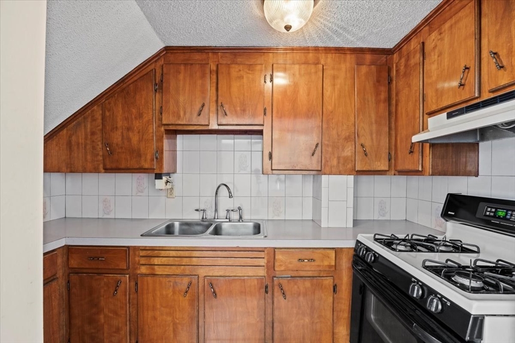 14 Grinnell Street Fall River, MA 02721 - Photo 31 of 41 a kitchen with stainless steel appliances wooden cabinets and a stove top oven