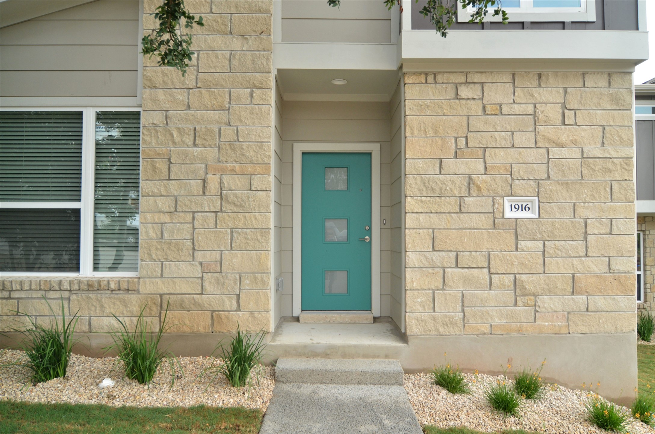 1916 Cleese Drive Austin, TX 78741 - Photo 2 of 36 A striking turquoise front door contrasts beautifully with the cream-colored stone facade of this inviting residence.