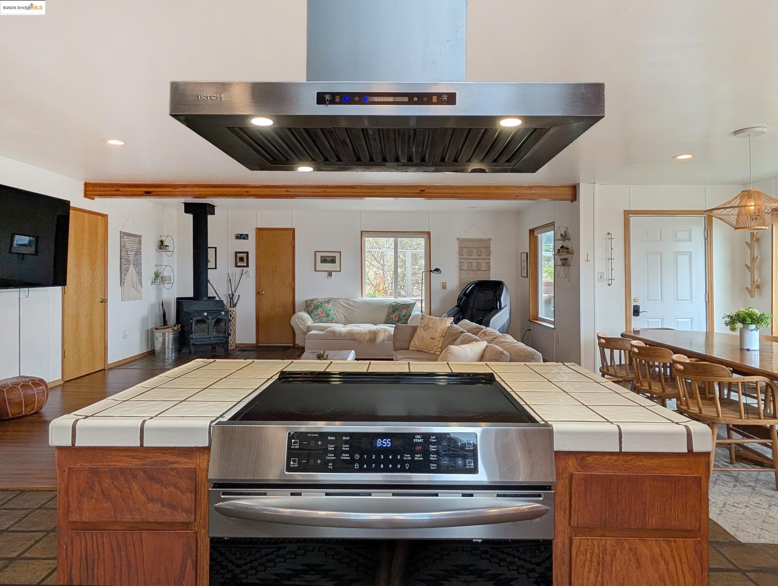 Kitchen featuring extractor fan, stainless steel electric range, recessed lighting, tile countertops, and a wood stove