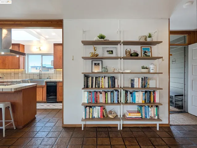 a open kitchen with stainless steel appliances a rug and a book shelf