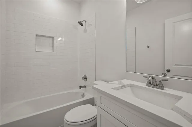 a bathroom with a granite countertop sink toilet a mirror and bathtub