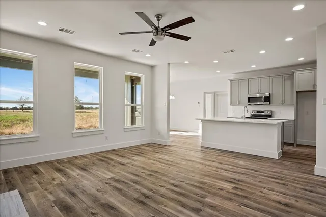 a view of kitchen with kitchen island wooden floor center island and stainless steel appliances