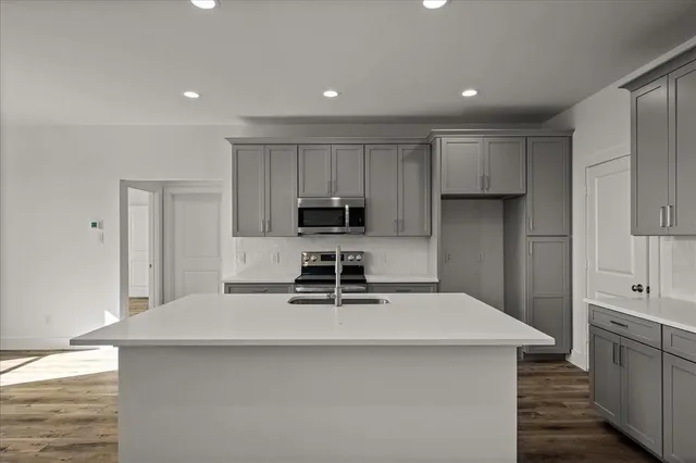 a kitchen with kitchen island a sink a stove a refrigerator and white cabinets