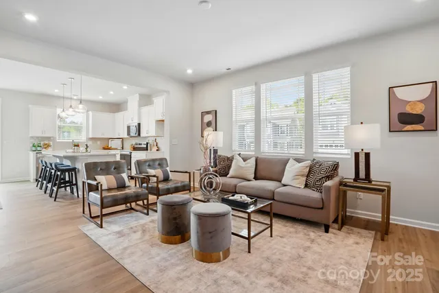 a living room with furniture kitchen view and a large window
