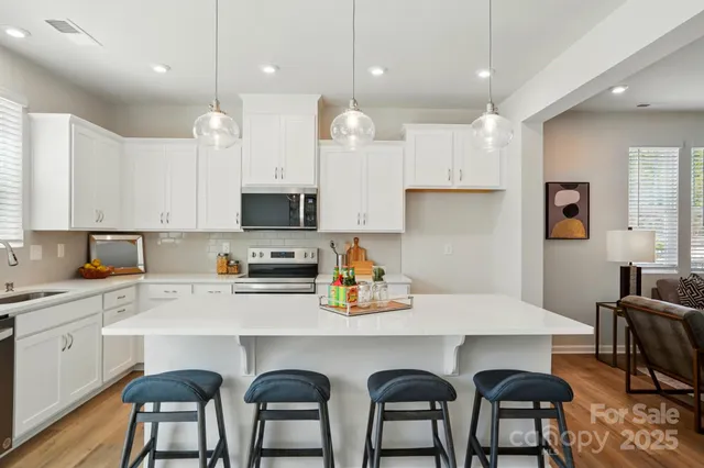 a kitchen with stainless steel appliances a dining table chairs sink refrigerator and microwave