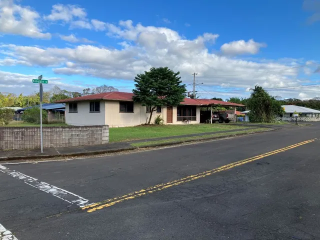 a front view of a house with a garden and trees