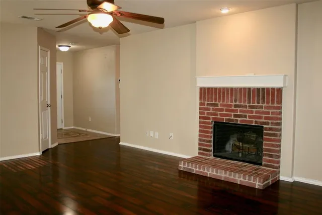 a living room with wooden floor and a fireplace