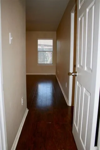an entryway in a hall with wooden floor and a window