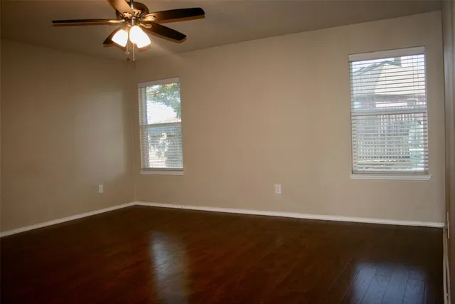 a view of empty room with wooden floor and fan