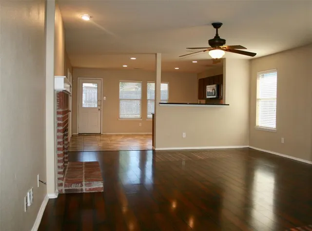 a view of an empty room with wooden floor and a window