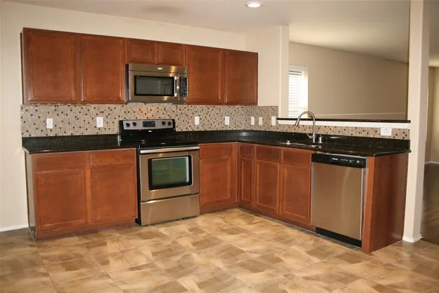 a kitchen with stainless steel appliances granite countertop a stove microwave and sink