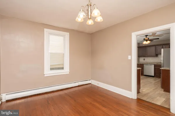 a view of a room with wooden floor kitchen chandelier and windows