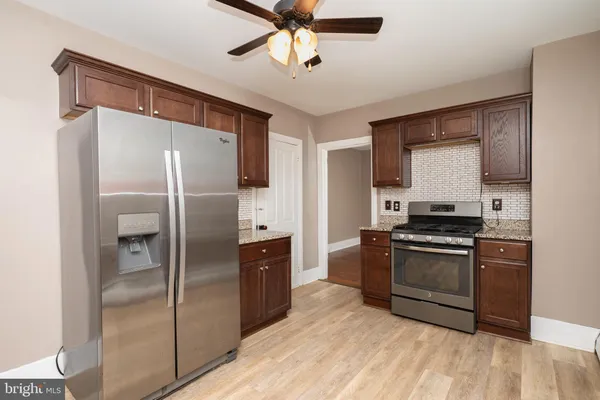 a kitchen with stainless steel appliances granite countertop a refrigerator a stove and a sink