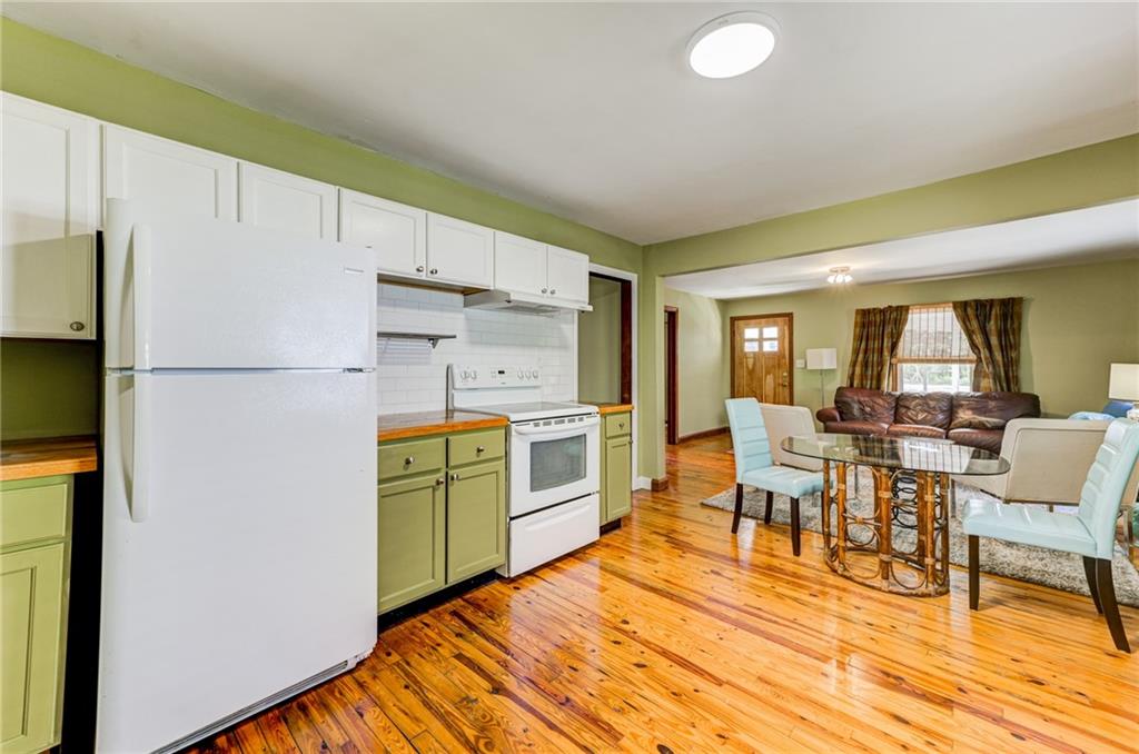 4100 Adrian Street Tucker, GA 30084 - Photo 9 of 23 a kitchen with granite countertop a refrigerator a stove a dining table and chairs with wooden floor