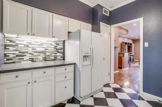 a kitchen with granite countertop white cabinets and refrigerator