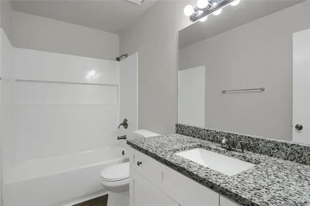 a bathroom with a granite countertop sink a toilet and shower