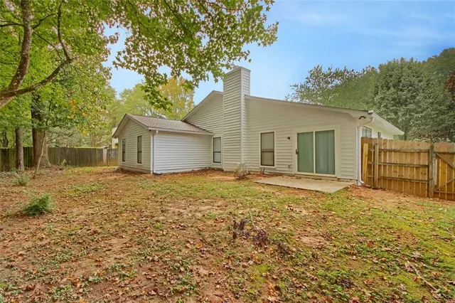 a backyard of a house with lots of plants and large trees