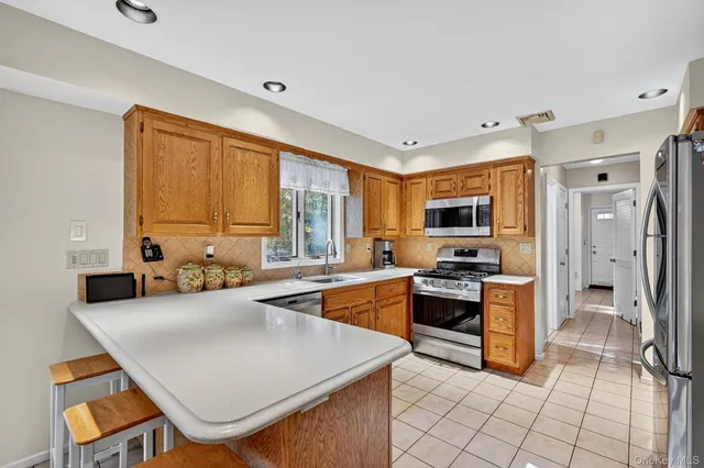 a kitchen with stainless steel appliances granite countertop a stove top oven a sink dishwasher a dining table and chairs with wooden floor