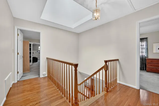 a view of a hallway with wooden floor and a chandelier