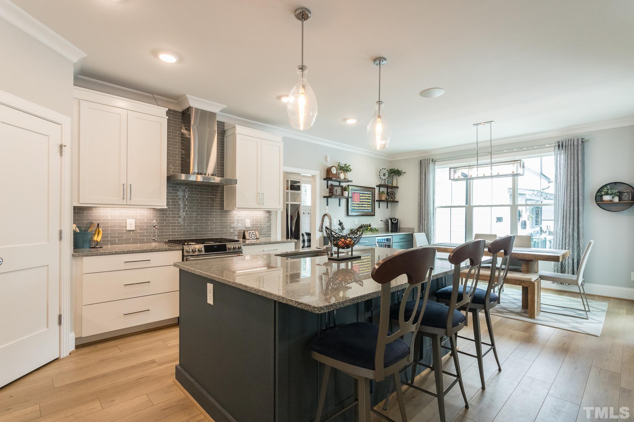 9117 Penny Road Raleigh, NC 27606 - Photo 11 of 54 a kitchen with stainless steel appliances granite countertop a stove top oven a sink a dining table and chairs with wooden floor