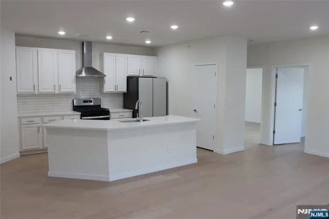 a large kitchen with stainless steel appliances a large counter top oven a sink and a refrigerator