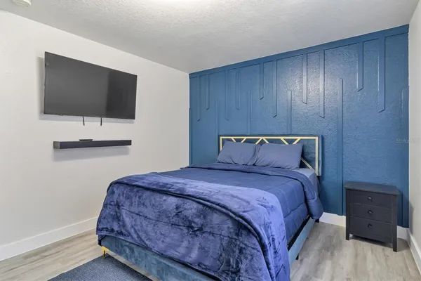 a bedroom with a bed and a flat tv screen on dresser
