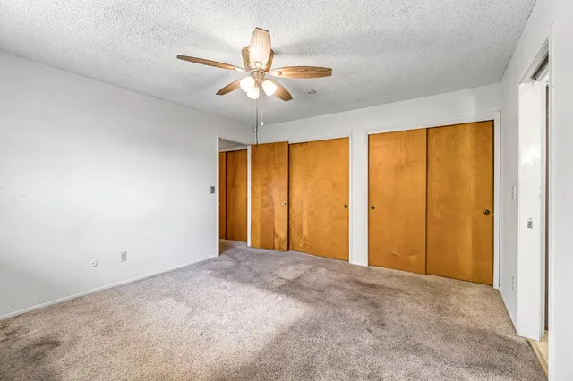 a view of an empty room with chandelier fan and a window