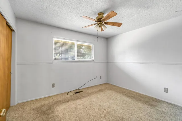 an empty room with a window and a ceiling fan