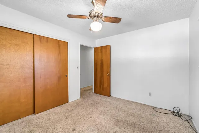 a view of a big room with windows and chandelier fan