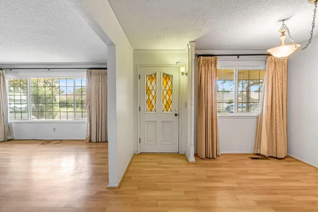 an empty room with wooden floor and windows