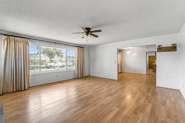 a view of an empty room with a window and wooden floor