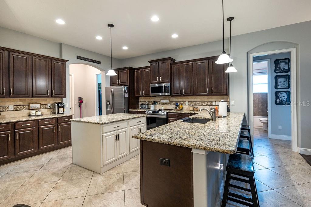 316 Old Mill Road Deltona, FL 32725 - Photo 8 of 64 a kitchen with kitchen island granite countertop wooden cabinets and refrigerator