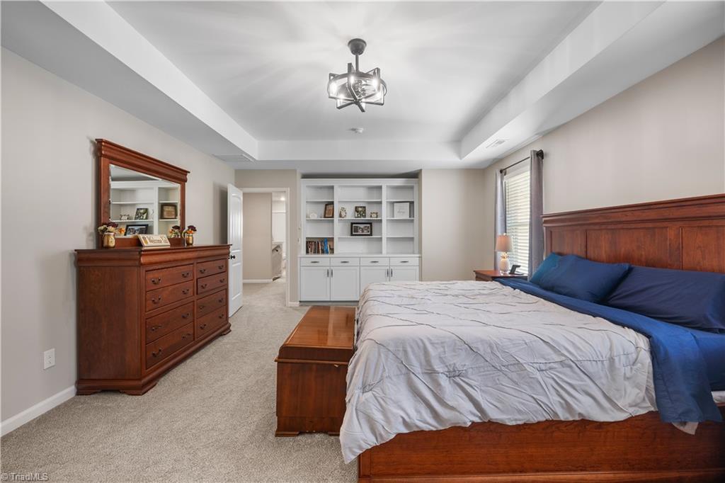 180 Moravian Advance, NC 27006 - Photo 19 of 34 This primary bedroom is generous in size and features a tray ceiling and custom built-ins.