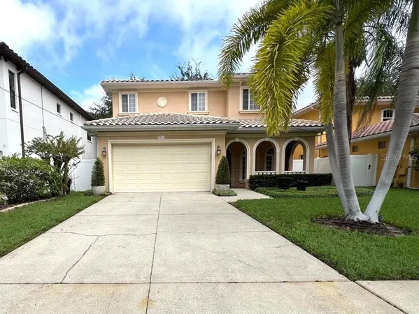 a view of a white house with a big yard plants and palm trees