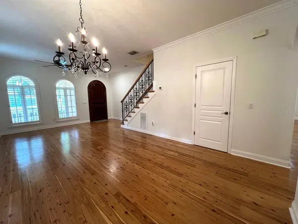a view of a room with wooden floor and chandelier