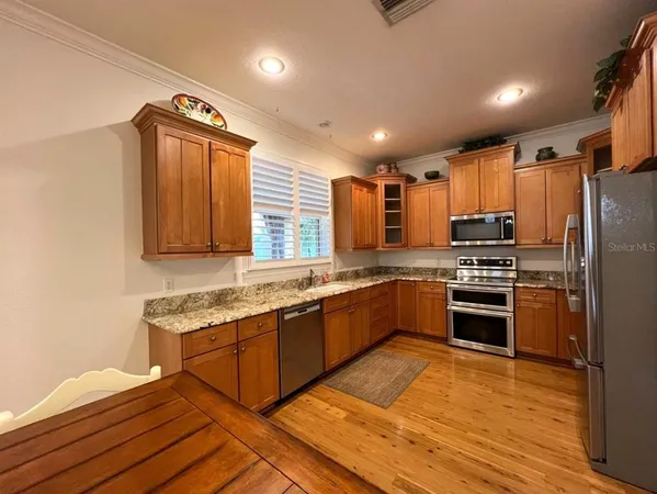 a kitchen with stainless steel appliances granite countertop a stove a sink dishwasher a refrigerator and cabinets with wooden floor