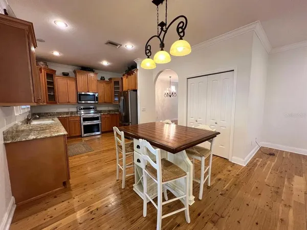 a kitchen with stainless steel appliances kitchen island granite countertop a table chairs and a wooden floor