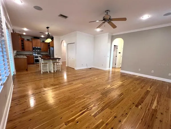 an empty room with wooden floor chandelier and windows