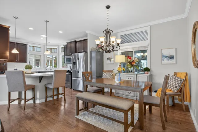 a dining room with wooden floor a chandelier a wooden table and chairs