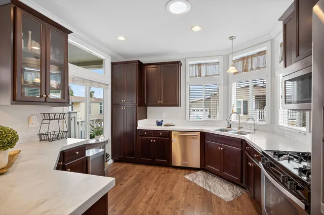a kitchen with a stove a sink a kitchen island with chairs and wooden cabinets