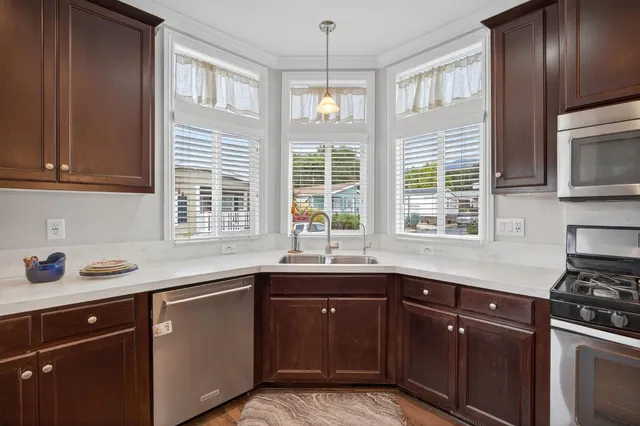 a kitchen with stainless steel appliances granite countertop a refrigerator a stove and a wooden floors