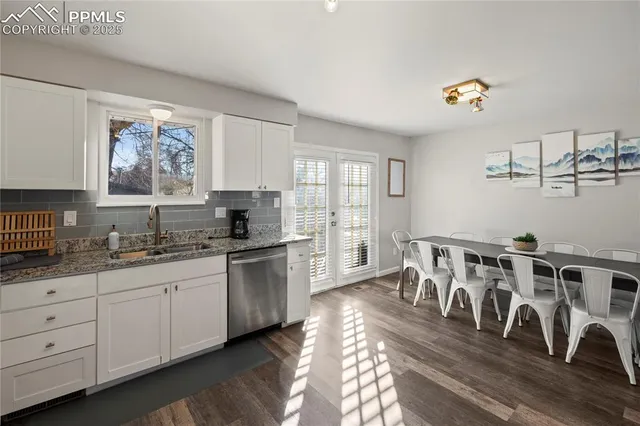 a kitchen with granite countertop a stove a sink and white cabinets with wooden floor