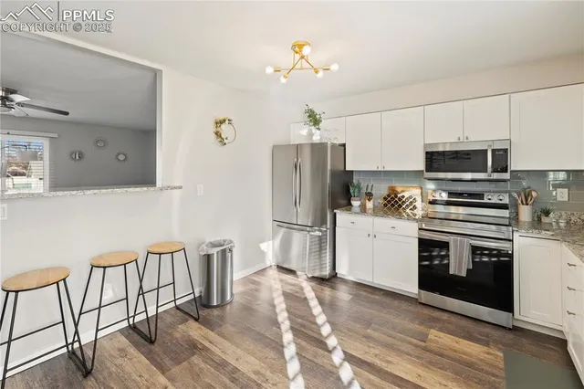 a kitchen with stainless steel appliances a stove a sink dishwasher a refrigerator and a dining table with wooden floor