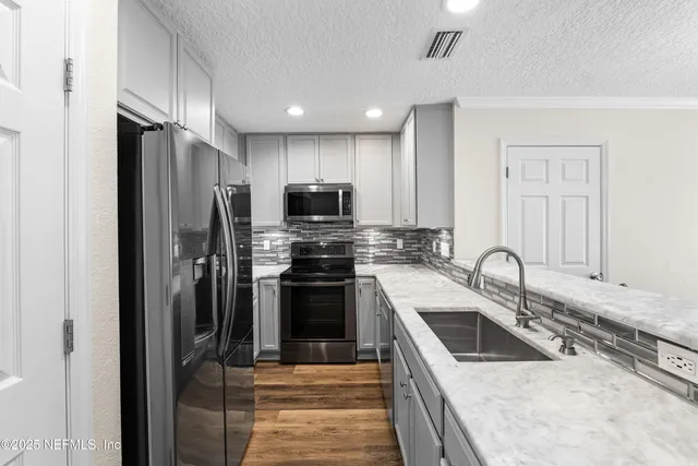 a kitchen with granite countertop white cabinets stainless steel appliances and a sink