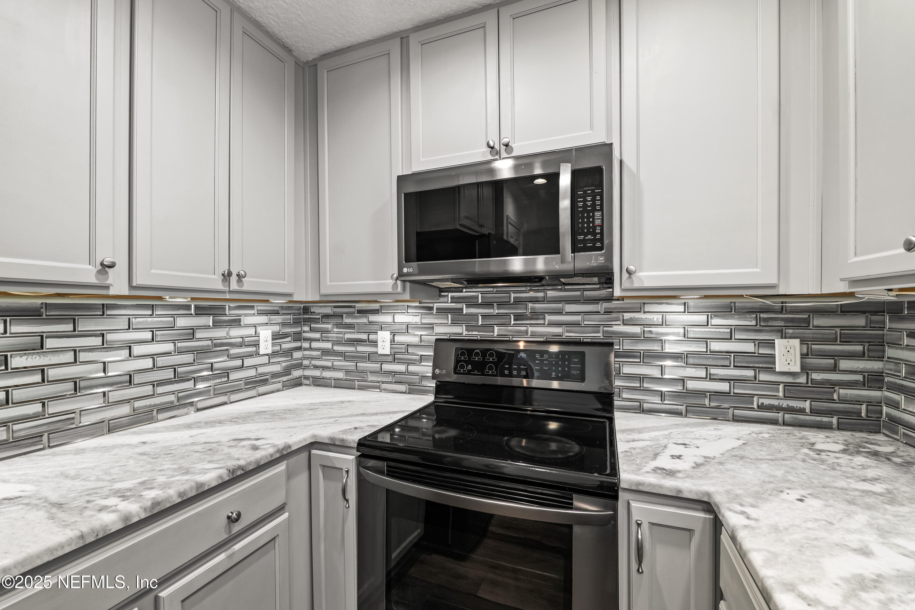295 Islander Circle St. Augustine, FL 32080 - Photo 17 of 34 a kitchen with granite countertop white cabinets stainless steel appliances and a sink