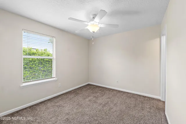 an empty room with closet and a ceiling fan