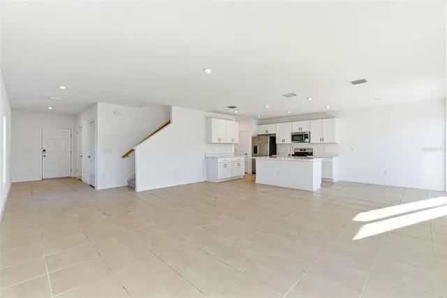 a view of open kitchen with white cabinets and white appliances