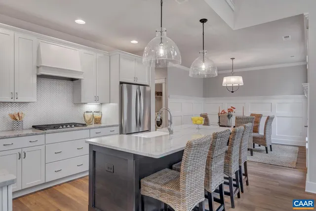 a kitchen with stainless steel appliances granite countertop a kitchen island a stove a table and chairs